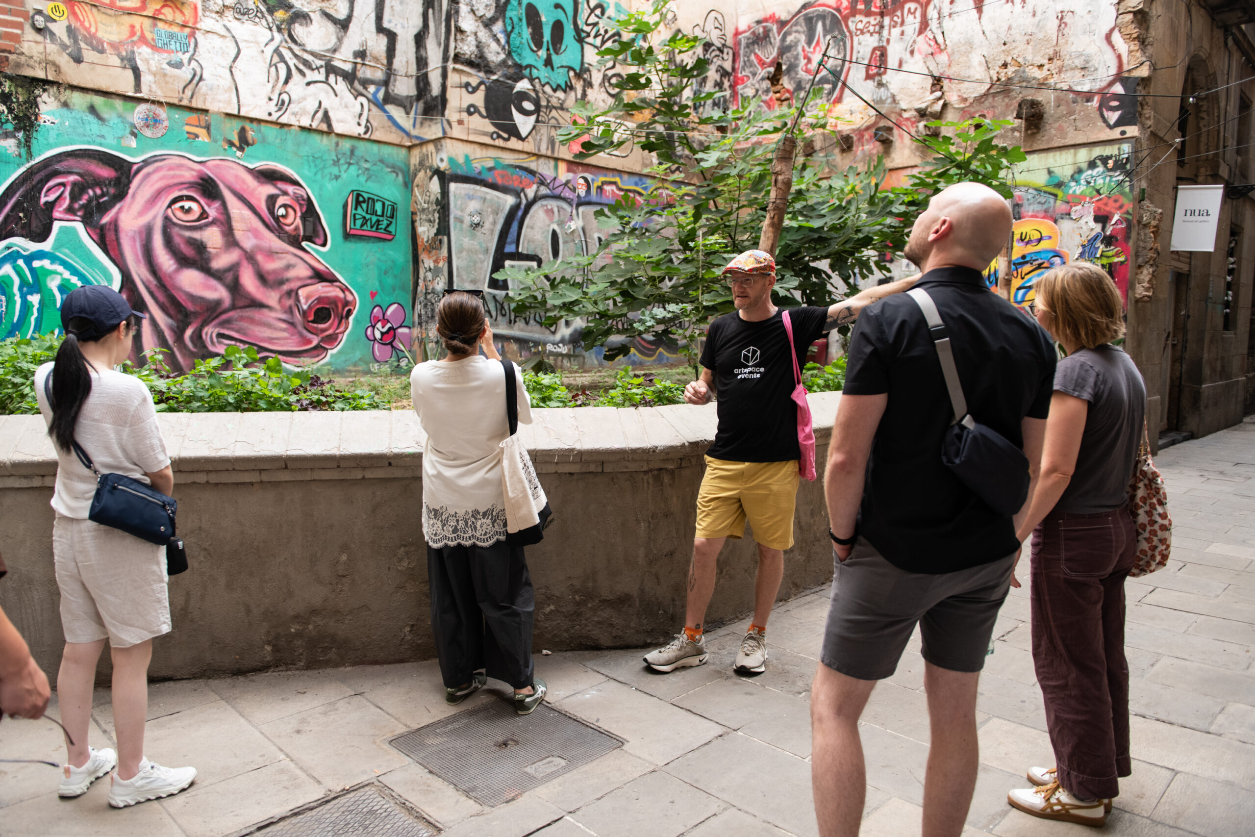 Street art tour guide showing a colourful graffiti mural to visitors in Barcelona